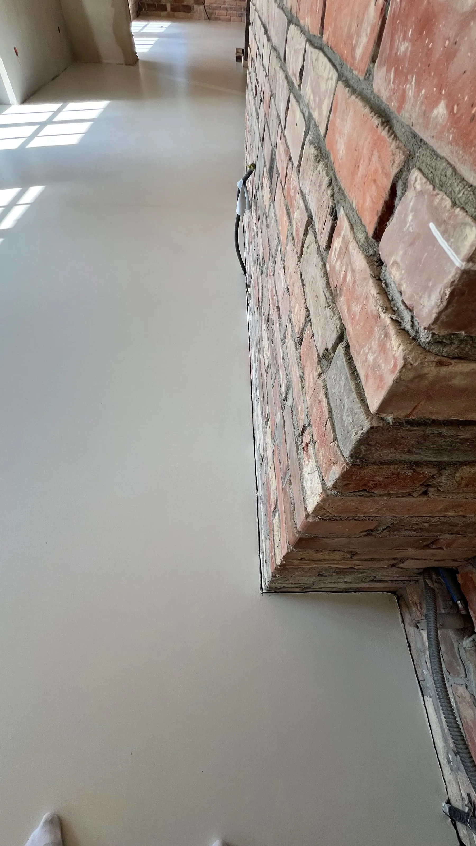 Ceglane kolumny i drewniany strop nad posadzką z mikrocementu